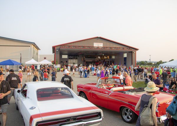 a crowd of people standing around a red and white car.