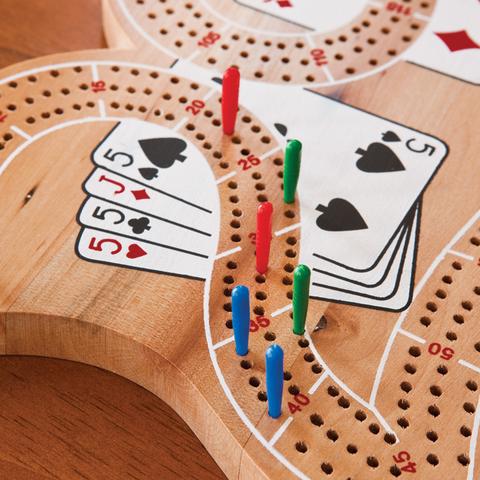 A wooden cribbage board with playing cards on it.