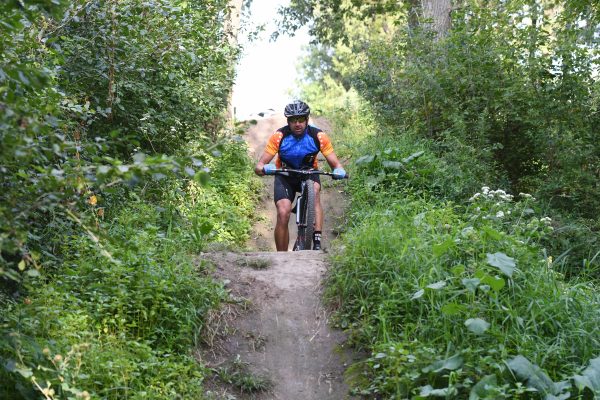 a man riding a bike down a dirt road.