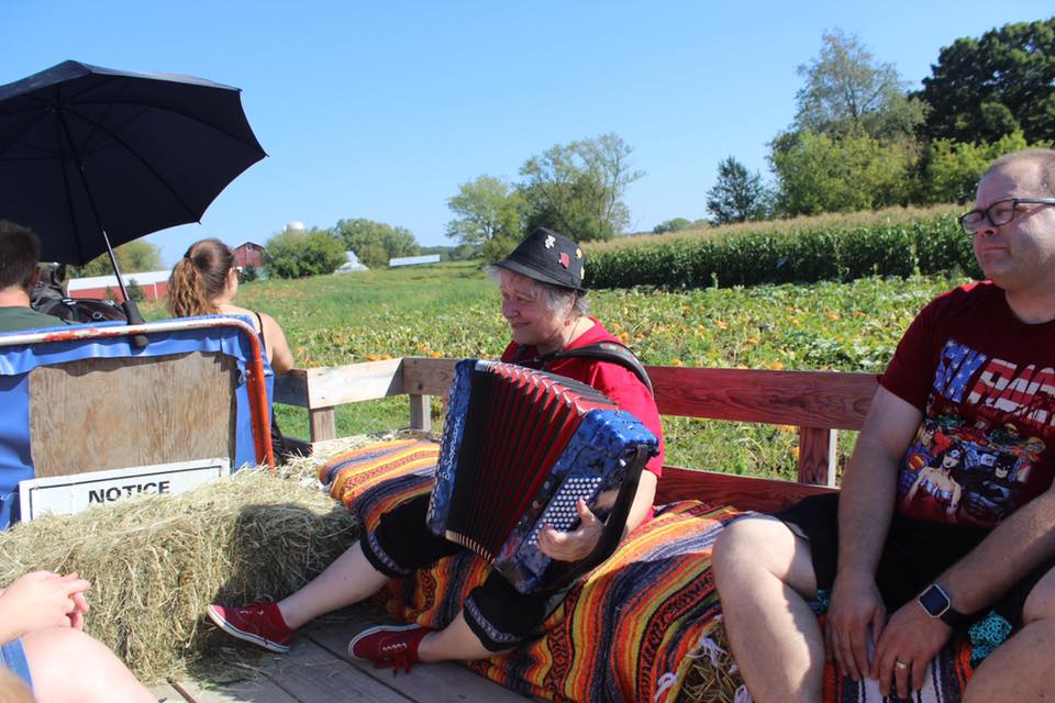 A group of people sitting on a bench playing an accordion.