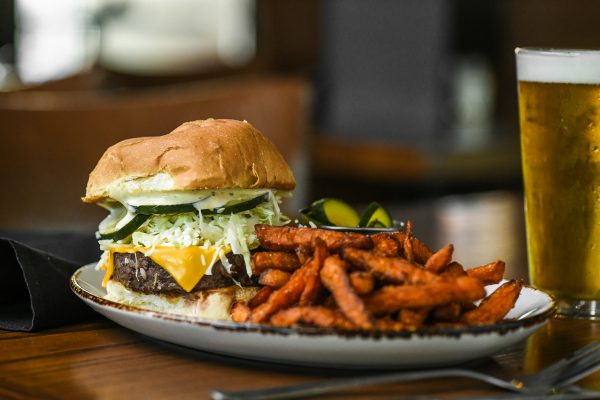 A burger and fries on a plate next to a glass of beer.