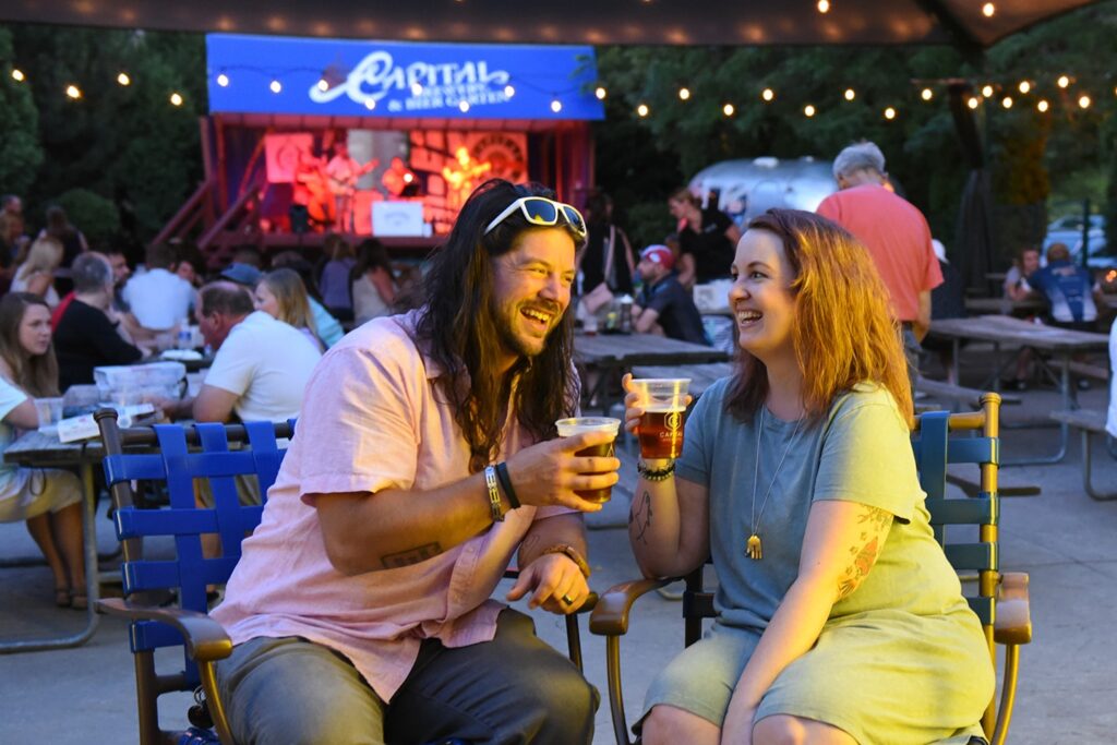 a man and a woman sitting at a table with beers