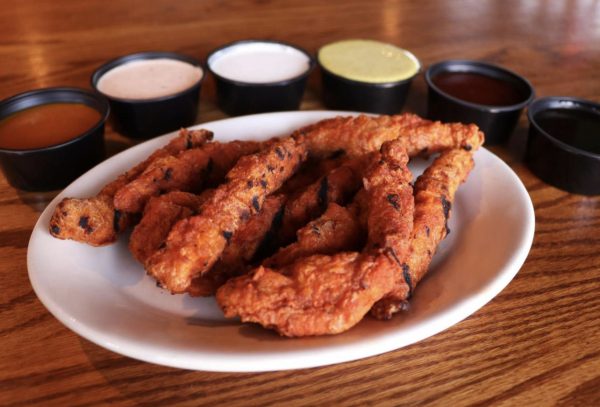 a white plate topped with fried chicken next to dipping sauces.