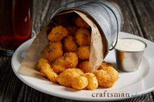 a white plate topped with tater tots next to a cup of sauce