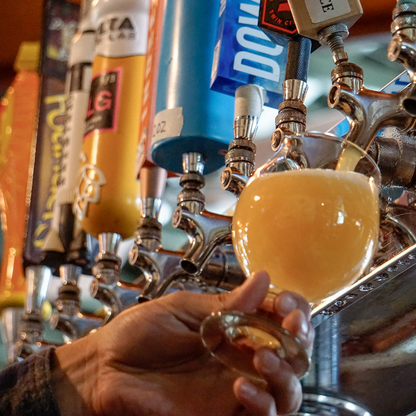 A person holding a glass of beer at a bar.