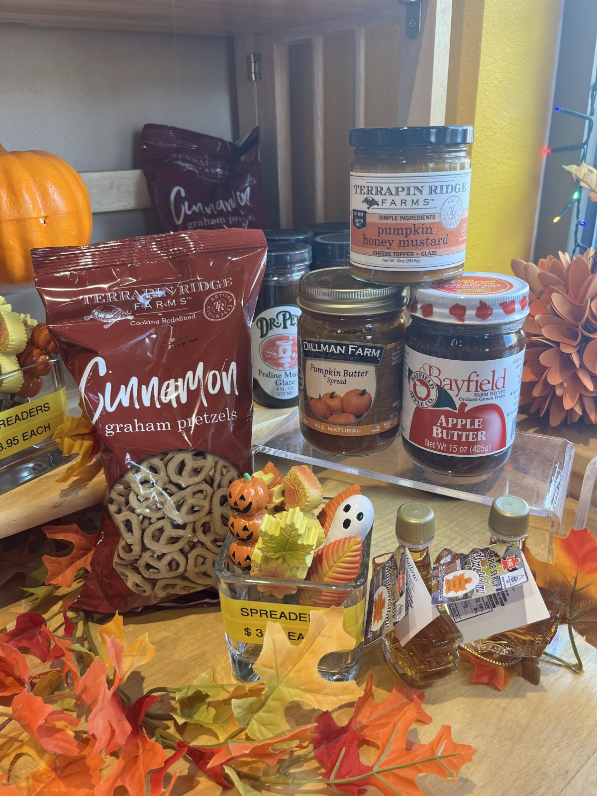 A variety of fall treats are on a table in front of a pumpkin.