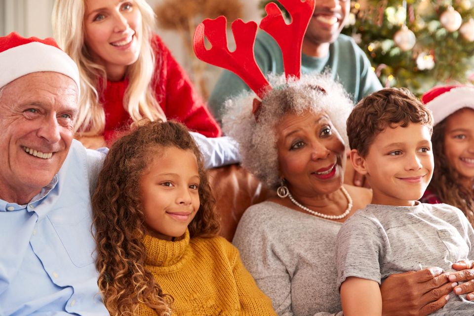 A family sitting on a couch with santa hats on.