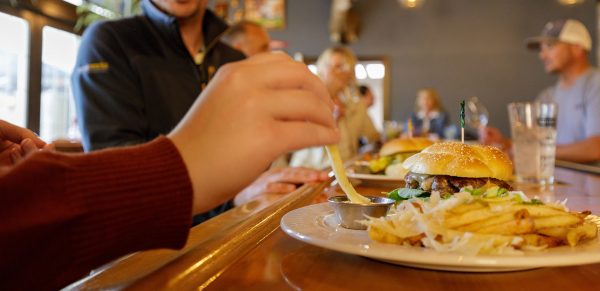 a group of people eating a burger at a bar.