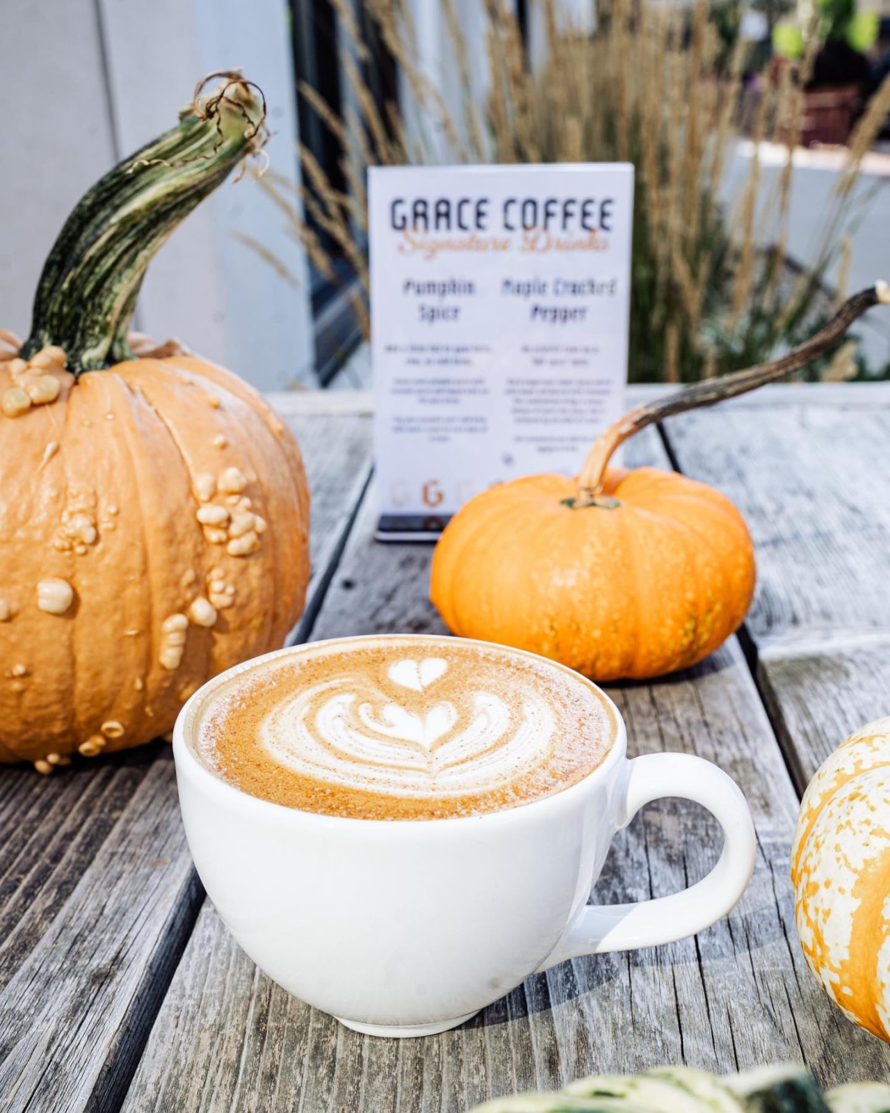A cup of coffee and pumpkins on a wooden table.