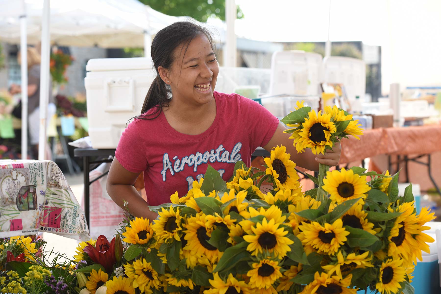 a woman standing next to a bunch of sunflowers