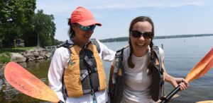 a couple of women standing next to each other on a lake