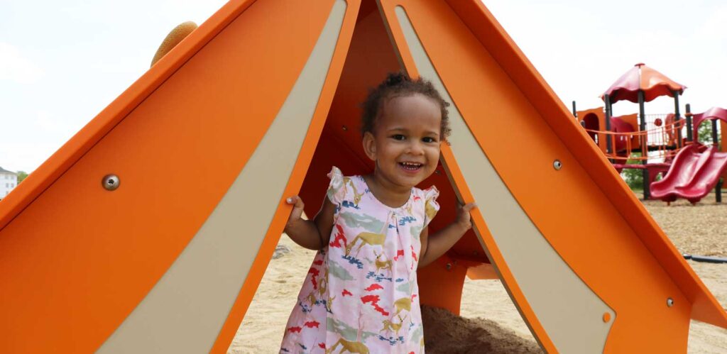 a little girl standing in front of a play structure