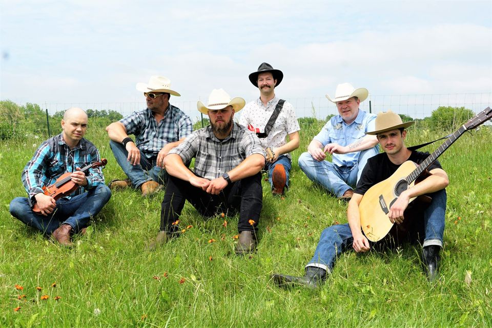 a group of men sitting on top of a lush green field.