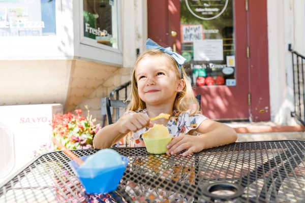 a little girl sitting at a table eating food.