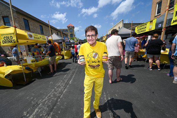 Barry Levenson, curator for the National Mustard Museum, stands on Hubbard Avenue with jars of mustard during the 2023 Mustard Day celebration.