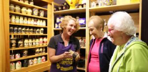 three women standing in front of a shelf full of jars