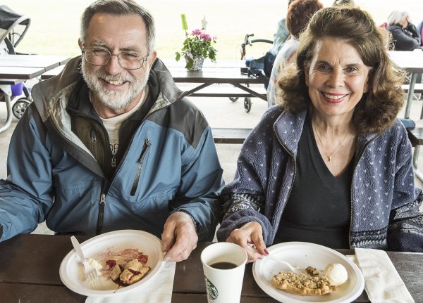 a man and woman sitting at a table with plates of food.