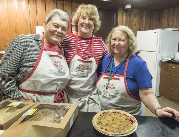 a group of three women standing next to each other in a kitchen.