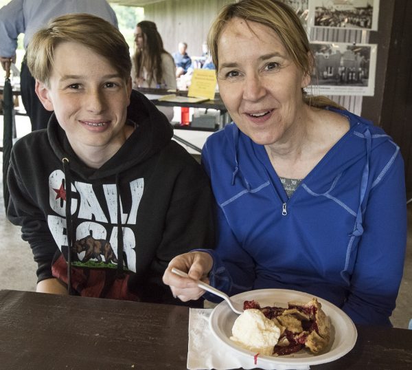 a woman and a boy sitting at a table with a plate of food.