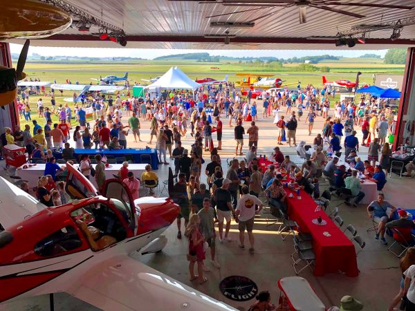 a crowd of people standing around a red and white plane.