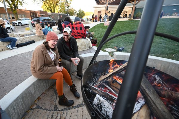 a couple of people sitting next to a fire pit.