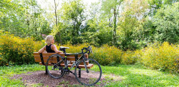 a woman sitting on a bench next to a bike.